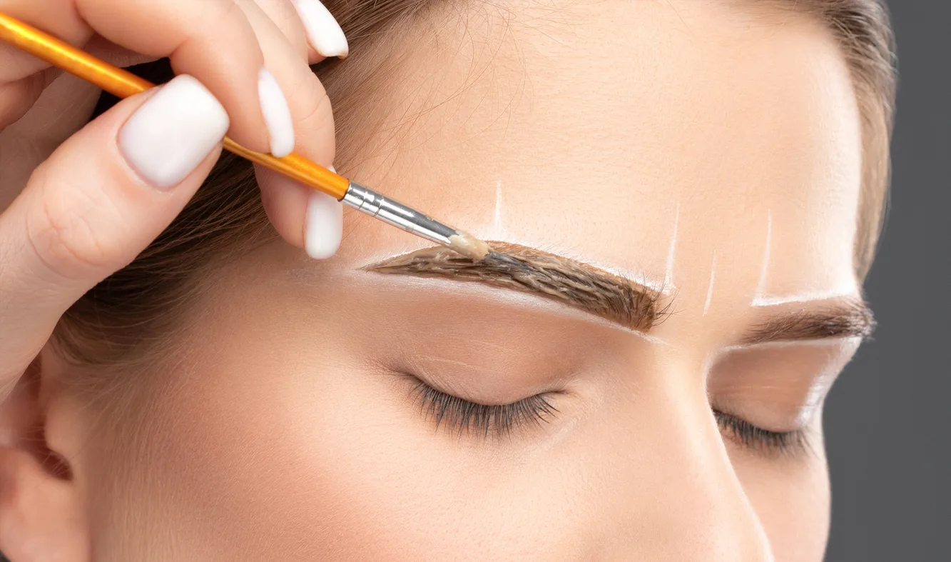 make up artist makes markings with white pencil for eyebrow and paints eyebrows. professional makeup and facial care.