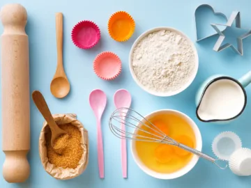 baking utensils and ingredients. egg yolk, brown sugar, milk, flour, whisker, spoons, cinnamon, bowl, rolling pin, cupcake paper cup, molds, sweet decoration elements. top view. flat lay