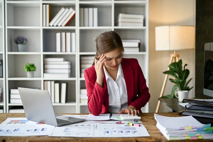 stressed asian businesswoman focuses on rechecking the business financial plan's report